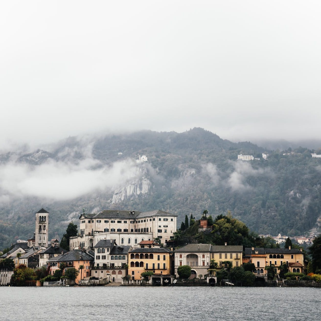 an island on a lake near a foggy mountain